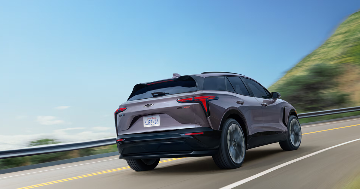 Silver Chevrolet Blazer EV driving on coastal highway with motion blur and scenic background