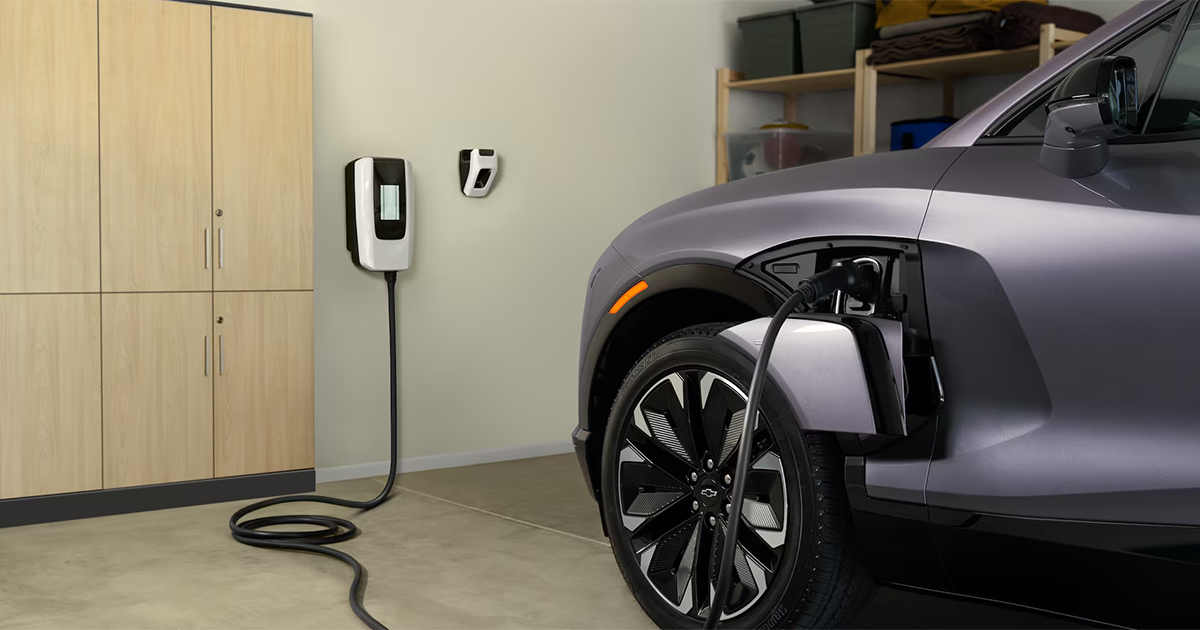 Silver Chevrolet Blazer EV charging in home garage with wall-mounted charging station and organized storage