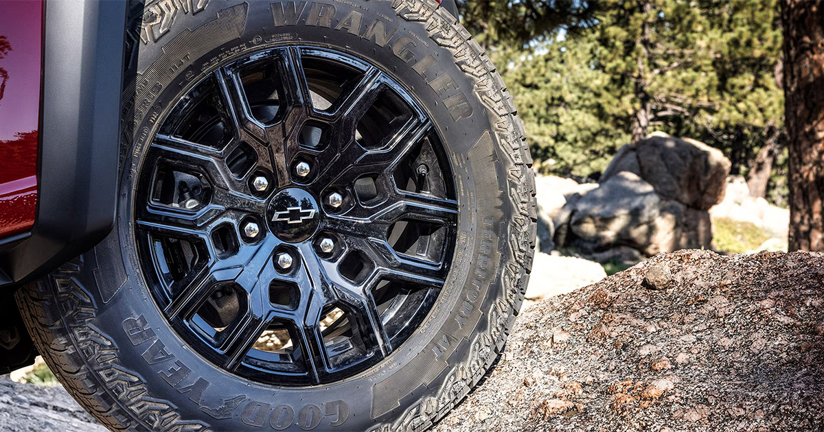 Close-up of black Chevrolet Colorado Wrangler all-terrain tire and dark alloy wheel on rocky terrain
