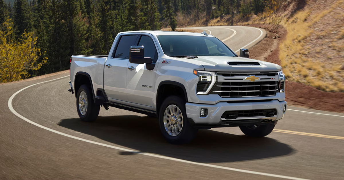 White Chevrolet Silverado HD pickup truck driving on winding mountain road