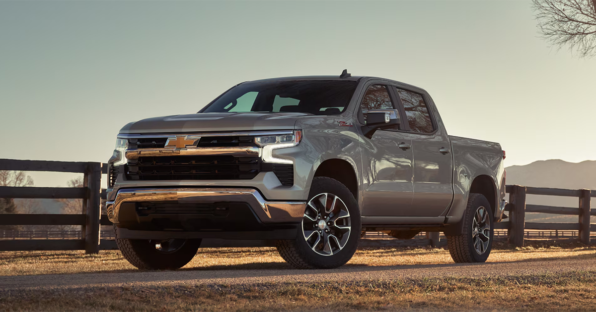 Silver 2025 Chevrolet Silverado 1500 crew cab parked at ranch fence during golden hour