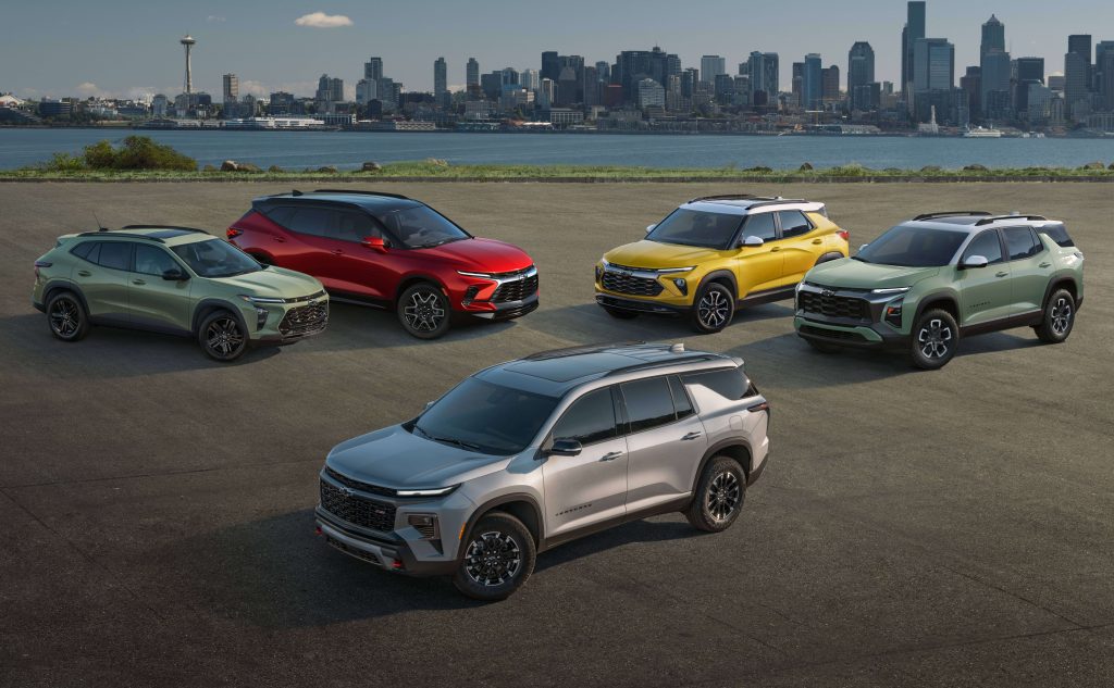 Five colorful Chevrolet crossover SUVs parked on an asphalt lot with the Seattle skyline in the background.