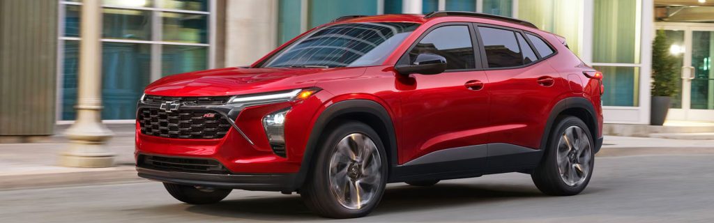 2026 Chevrolet Equinox RS in red driving through a city street, showcasing sporty styling, LED lighting, and modern SUV performance.