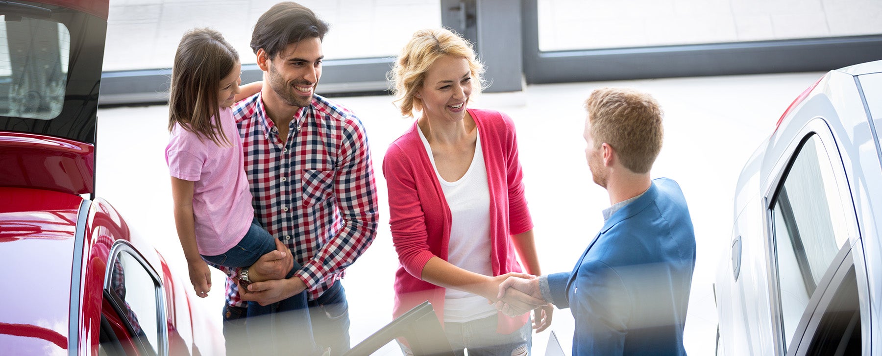 A salesperson shaking hand with a lady coming with her family.